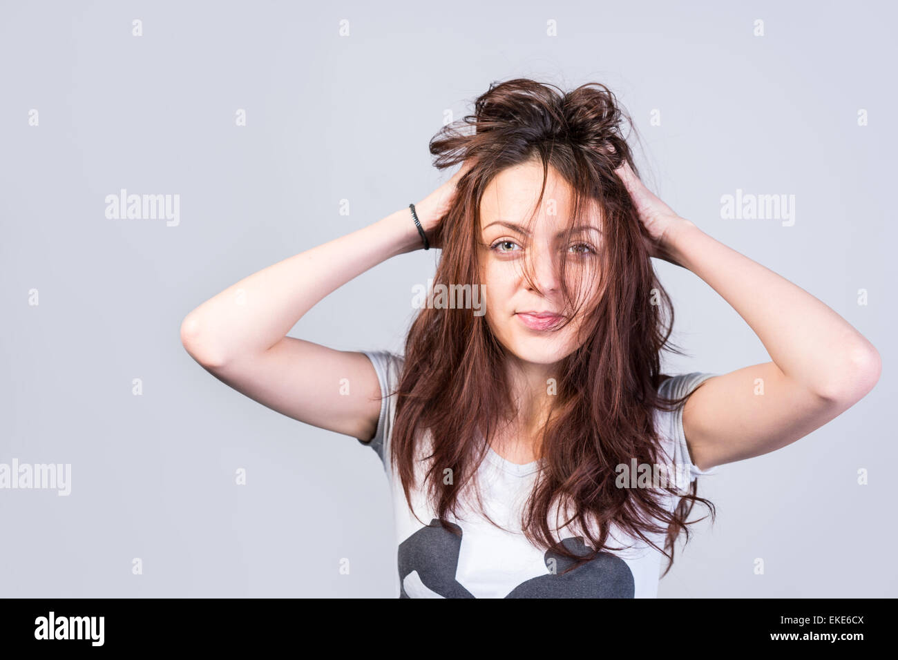 Jeune femme aux cheveux ébouriffés malpropre tenant la main à sa tête avec une expression ironique à son apparence échevelée, isolé o Banque D'Images