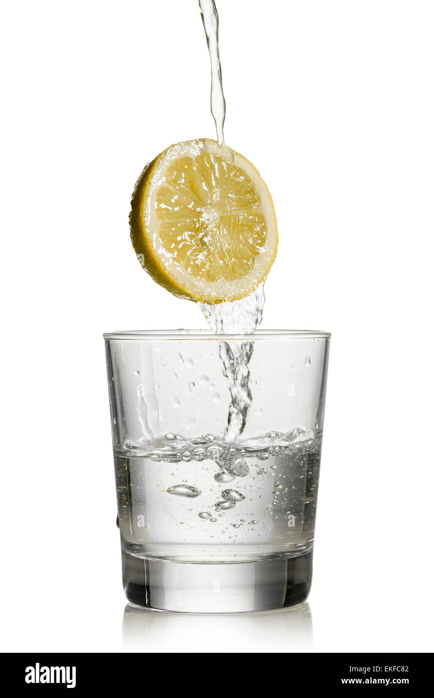 L'eau s'écoule plus de citron et remplir un verre sur fond blanc Banque D'Images