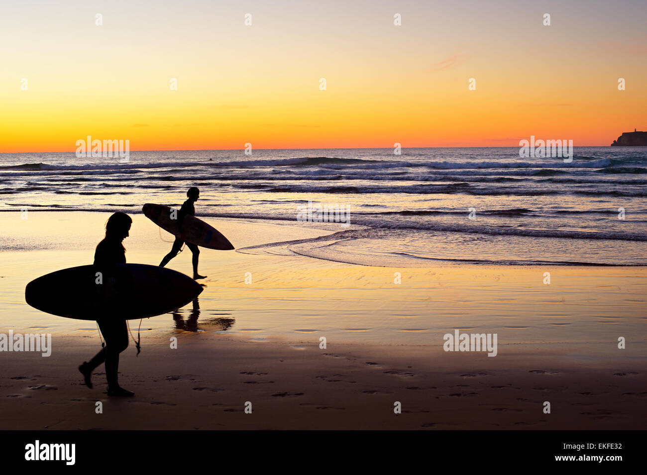 Deux surfeurs s'exécutant sur la plage au coucher du soleil. Le Portugal a l'une des meilleures scènes de surf en Europe Banque D'Images