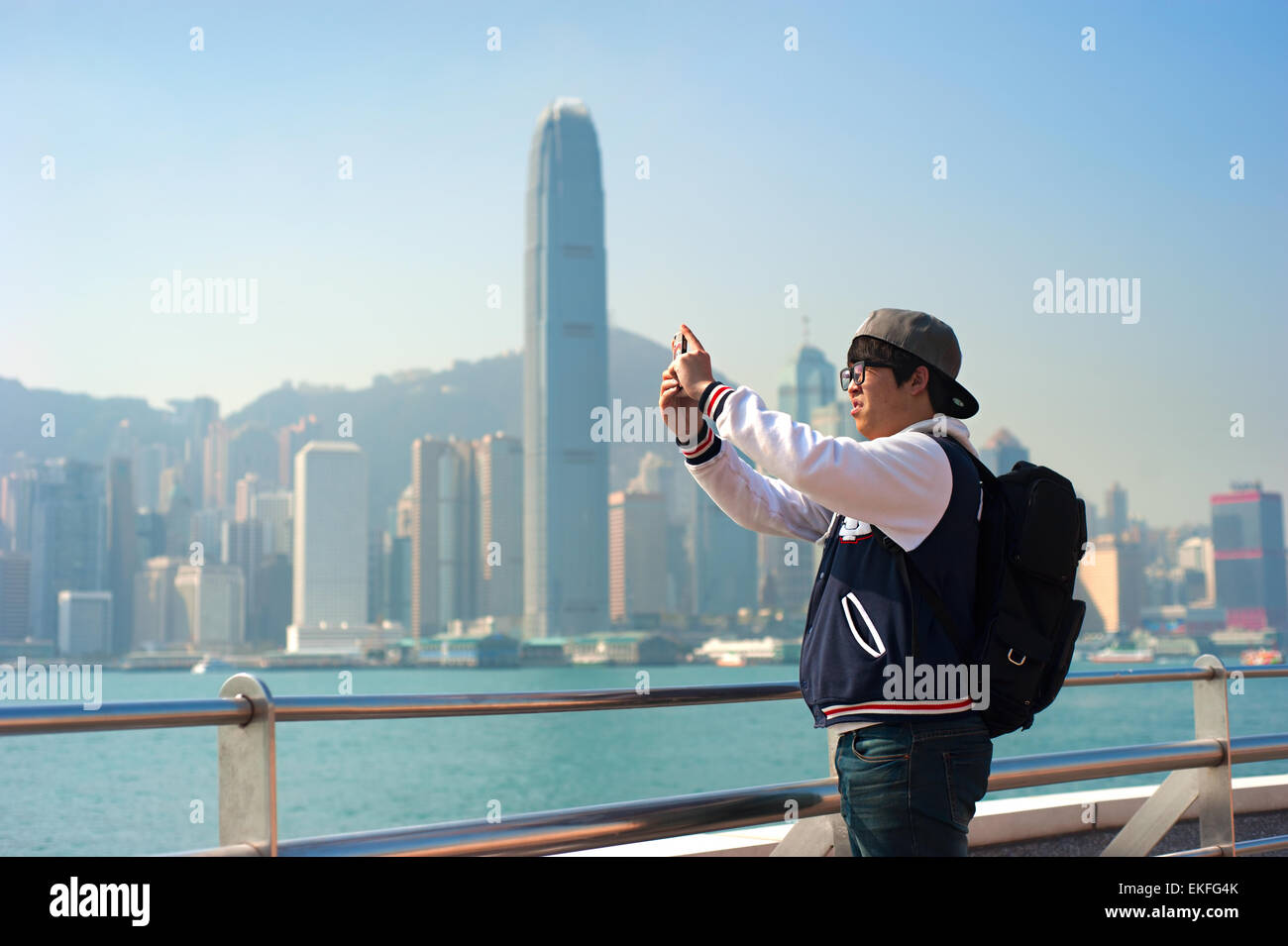 Homme non identifié de prendre une photo de l'horizon de Hong Kong par son téléphone. L'industrie du tourisme un importan Banque D'Images