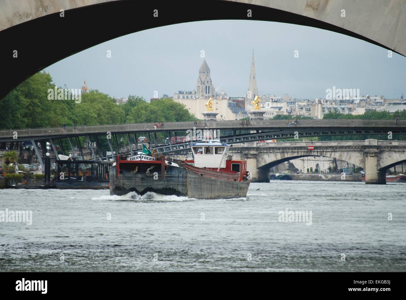 Péniche sur la Seine passant sous un pont avec la Tour Eiffel en arrière-plan, Paris, France. Banque D'Images