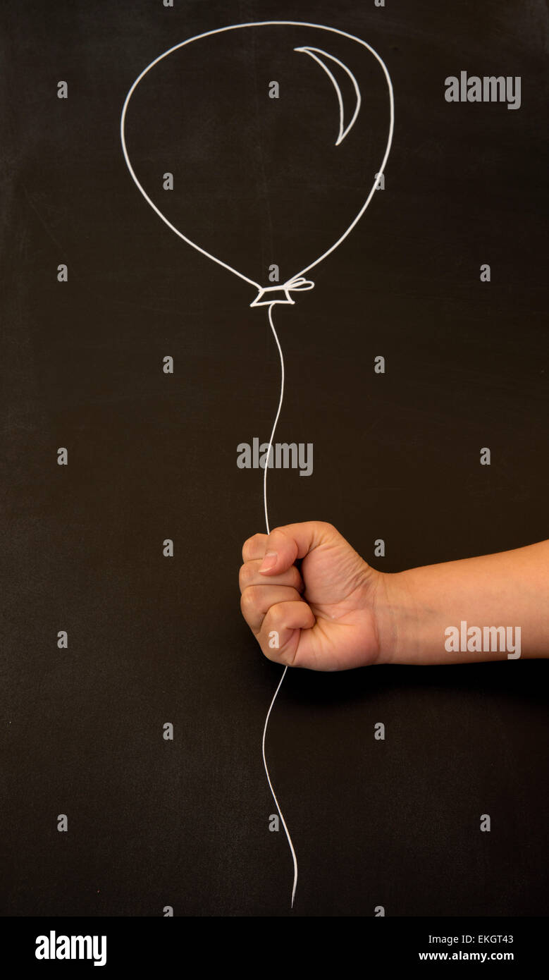 Holding balloon on blackboard Banque D'Images