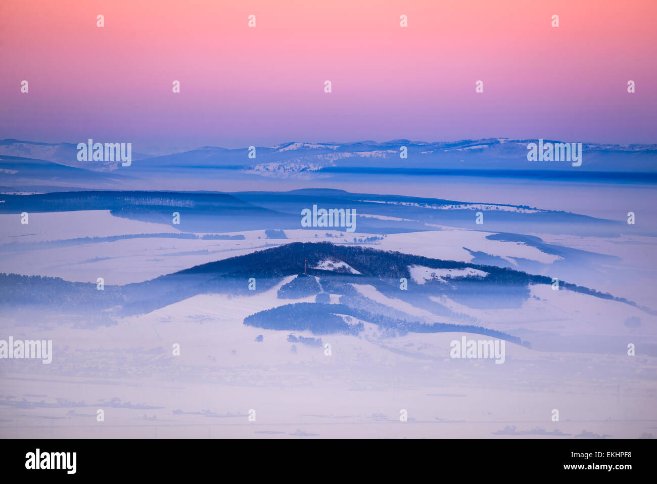 Paysages d'hiver coucher du soleil dans la dépression dans le Burzenland Carpates (Brasov, la Transylvanie en Roumanie) avec de la neige et du brouillard. Banque D'Images