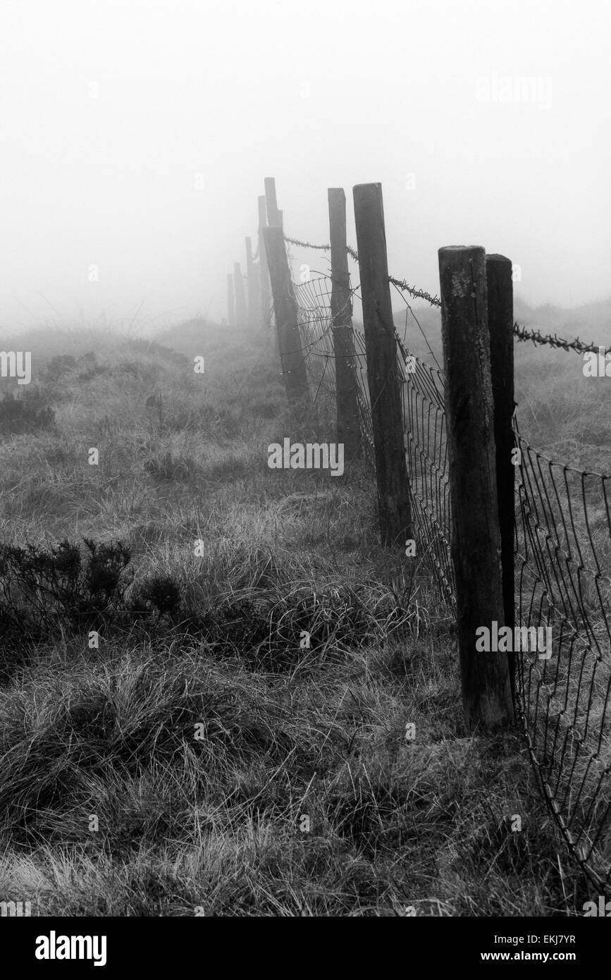 Tourné en noir et blanc d'une vieille clôture de disparaître dans le brouillard sur le sommet de la Dent, Cleator-Moor, Cumbria, Angleterre Banque D'Images