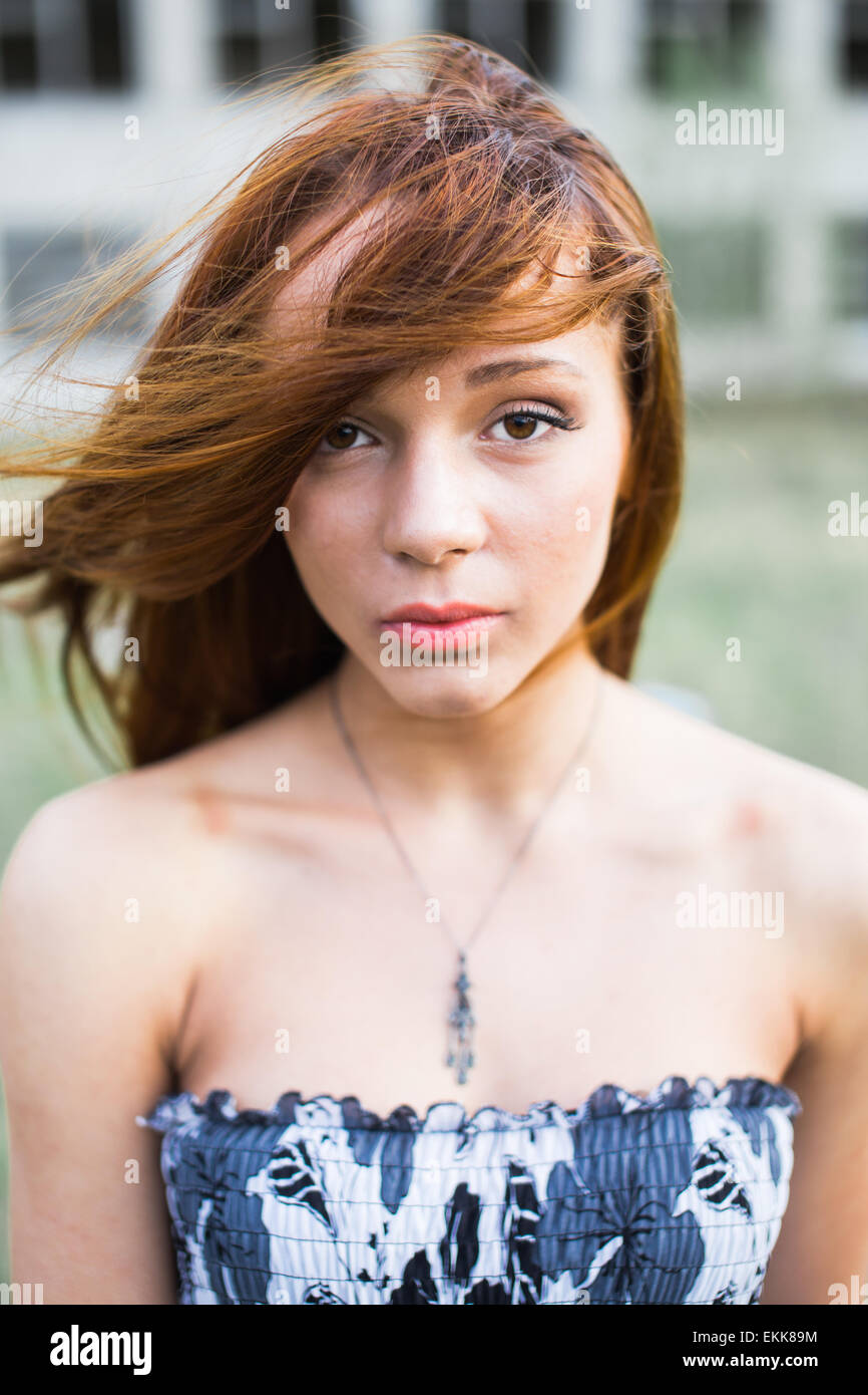 Portrait d'une jolie rousse jeune femme en robe à fleurs à l'appareil photo. Déménagement cheveux au vent Banque D'Images