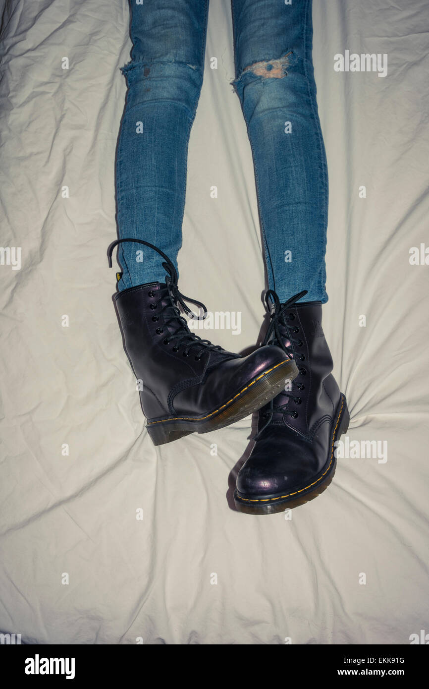 Les jambes de l'adolescente couchée sur le lit en Doc Martens. Banque D'Images