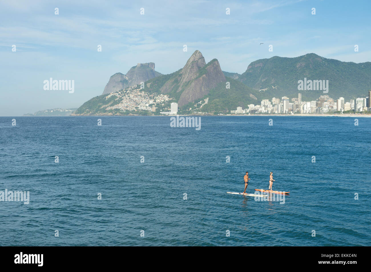 RIO DE JANEIRO, Brésil - le 22 mars 2015 : une paire de passionnés de stand up paddle le long de l'eau à la plage d'Ipanema. Banque D'Images