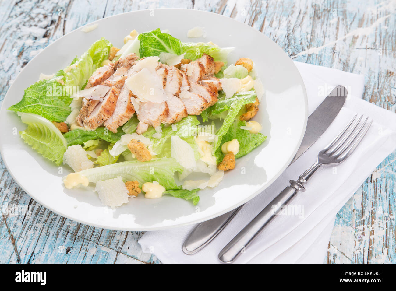 Salade césar avec poulet et verts sur table en bois Banque D'Images
