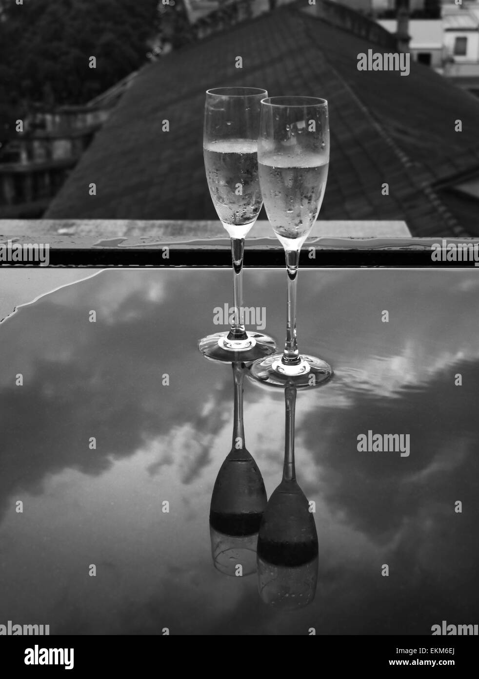 Verres de champagne sur une table sous la pluie avec des réflexions Banque D'Images