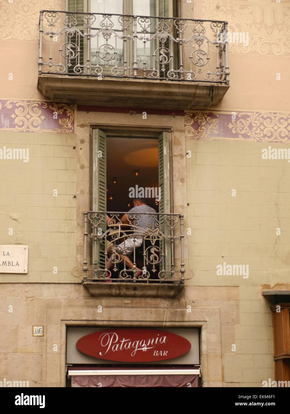 Un homme assis dans une fenêtre balcon à Barcelone, Espagne Banque D'Images