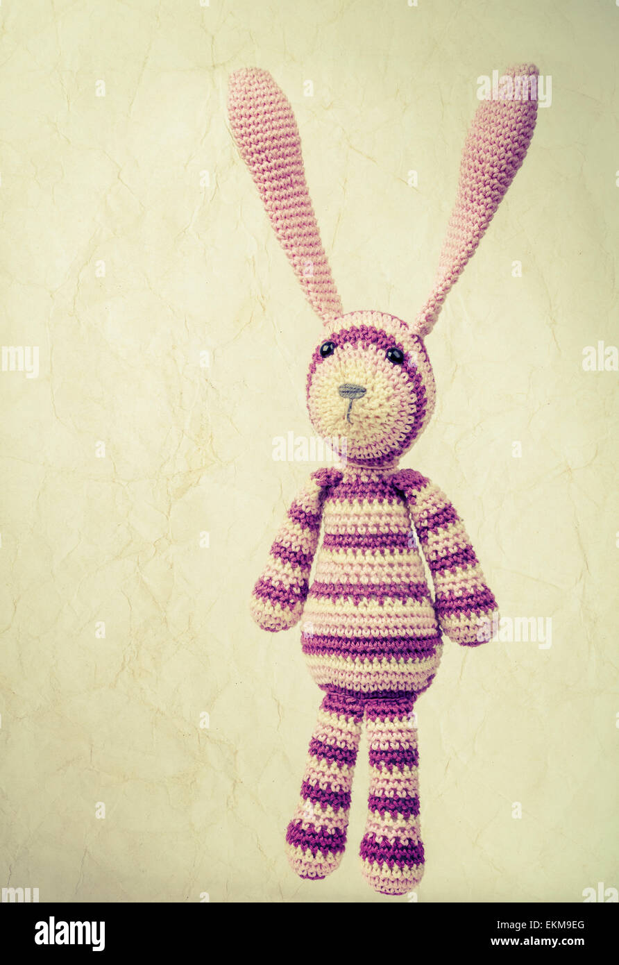 Drôle de jouet de lapin tricoté avec les oreilles portrait, photo aux tons vintage style rétro avec effet tonique et old paper texture Banque D'Images