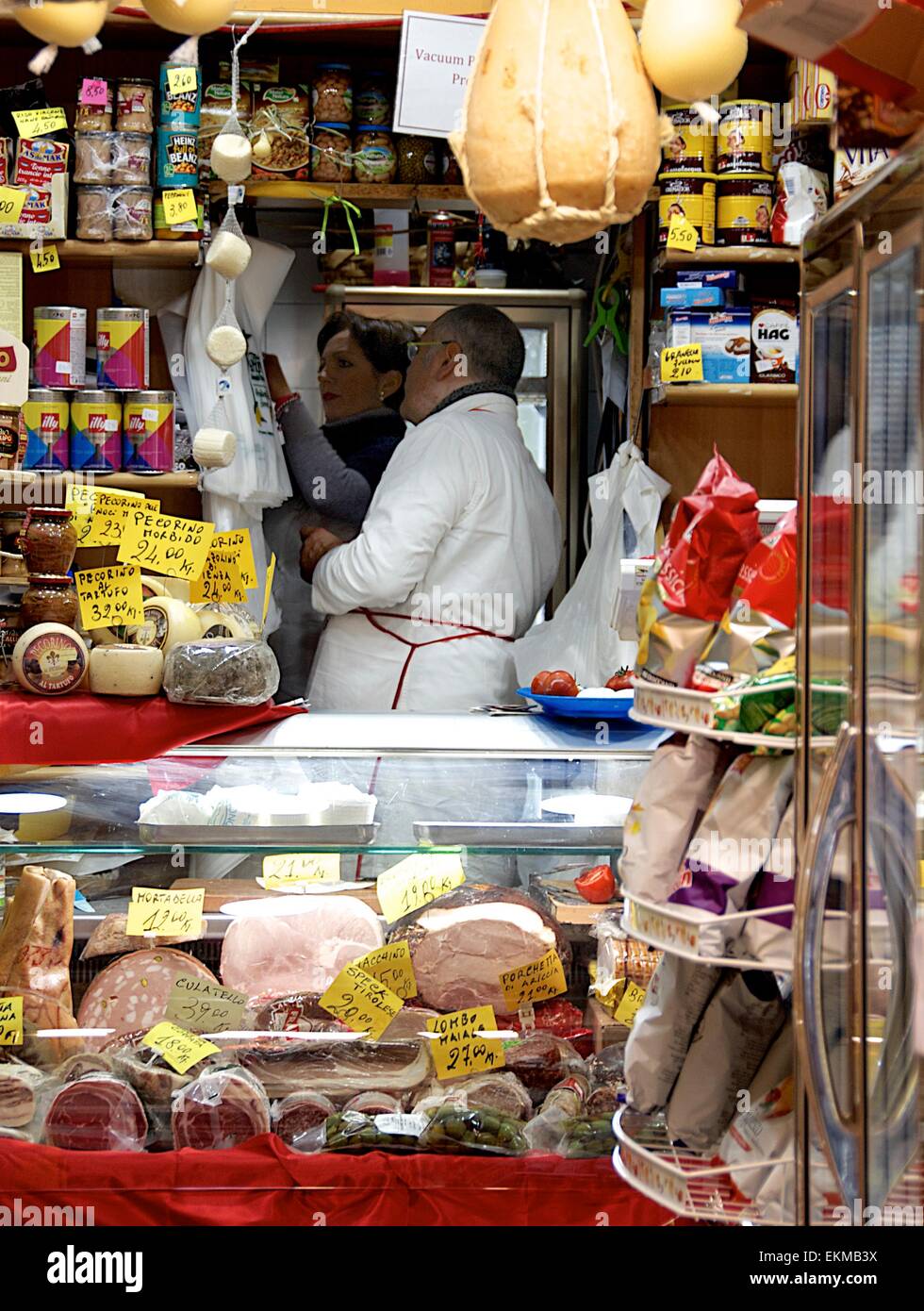 Un commerçant à l'arrière d'une épicerie fine De produits régionaux italiens, y compris viandes et fromages Banque D'Images