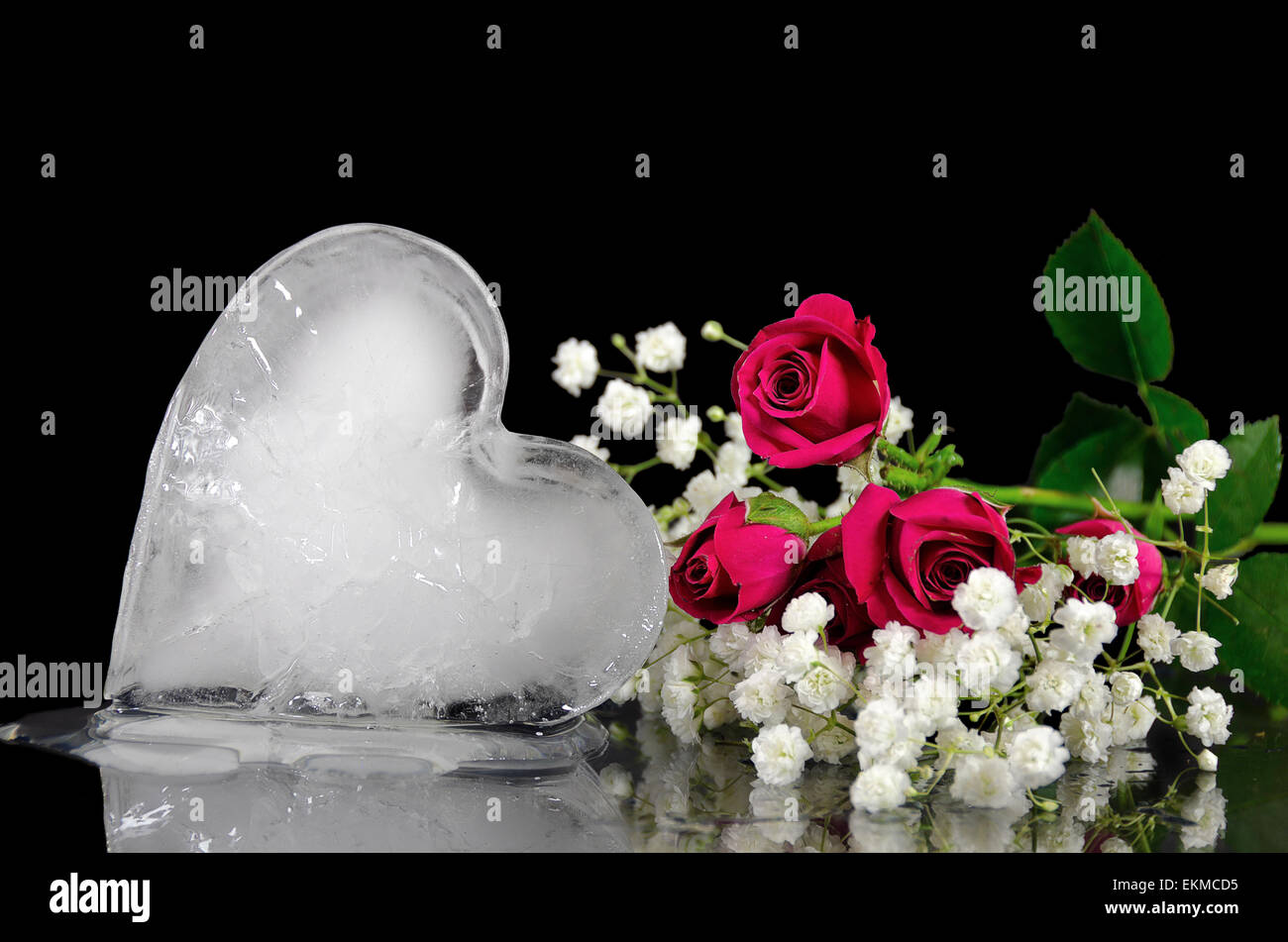 Coeur de glace fondante sur miroir avec bouquet de rose rouge. Banque D'Images