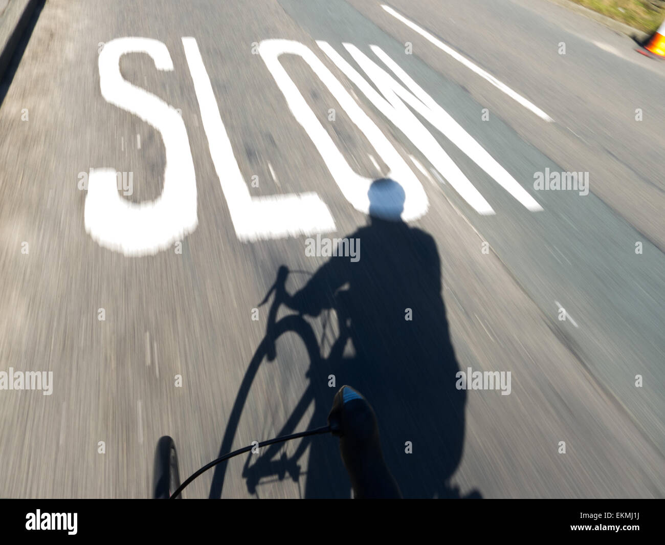 Cyclisme vers SLOW sign painted on road Banque D'Images