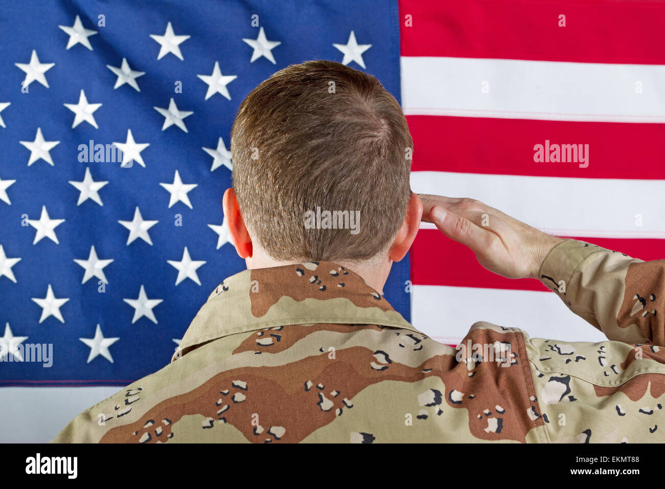 Image Gros plan homme soldat, dos à la caméra, saluant le drapeau des États-Unis d'Amérique alors que l'intérieur ne portaient pas entendre. Banque D'Images