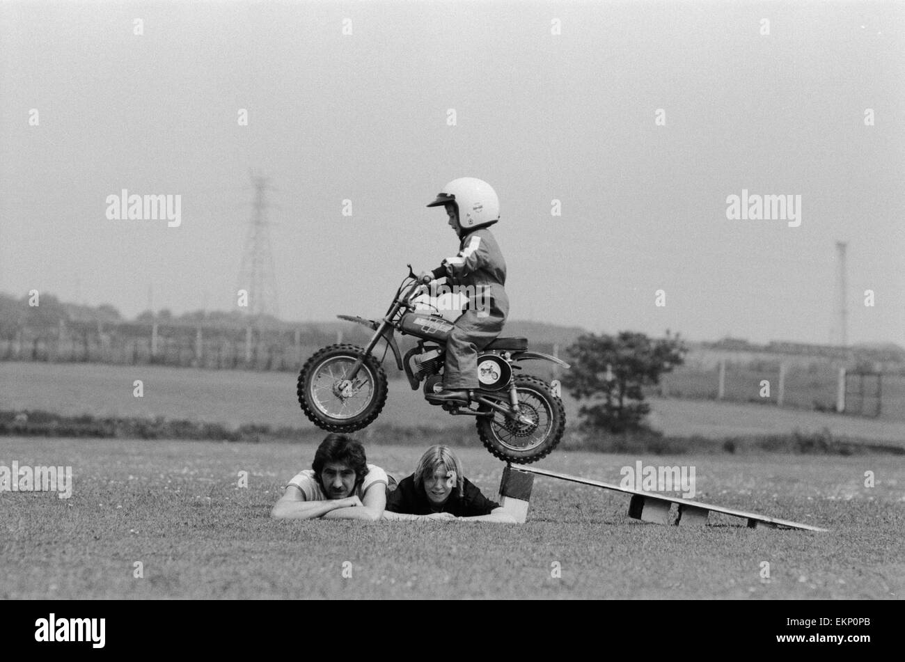 Quatre ans Jarno Barratt de Corby, Northamptonshire, exécute une cascade sur sa moto Italjet 50 cc, à l'aide de ses parents comme accessoires. 10 juin 1979. Banque D'Images