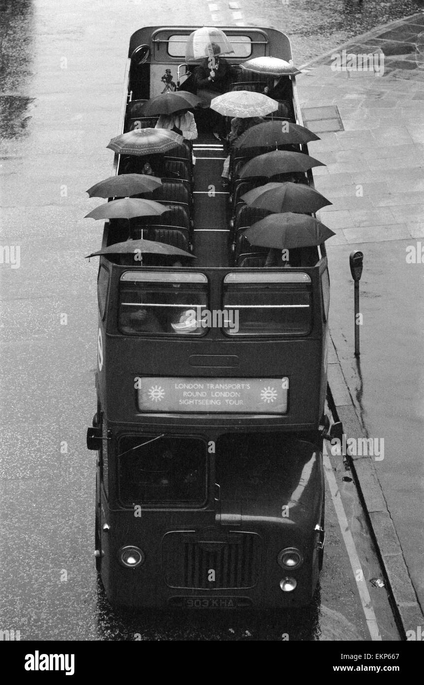 Les touristes s'asseoir sous leur parapluie sur le pont supérieur d'un bus à toit ouvert au cours d'une visite touristique de Londres sous la pluie. 28 octobre 1976. Banque D'Images