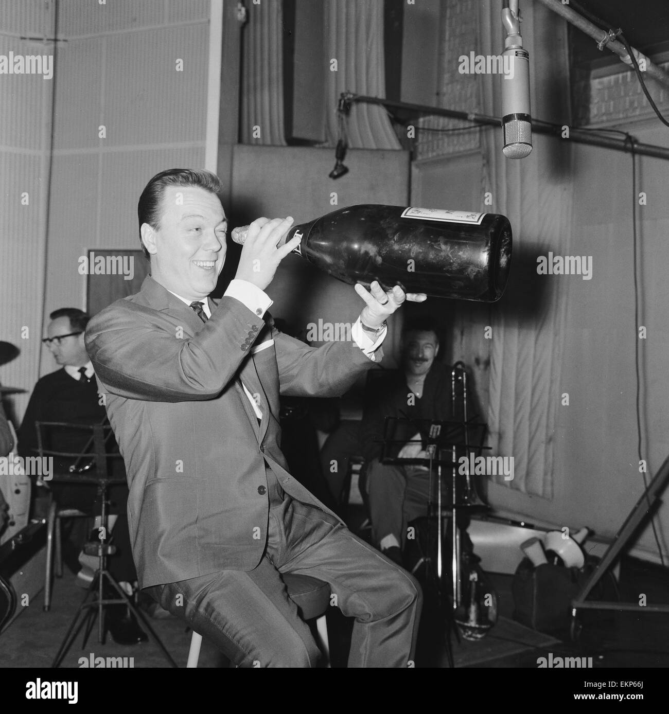 L'anglais Matt Monro avec une taille gigantesque bouteille de champagne comme il travaille sur son dernier album dans les studios d'enregistrement à Londres. 27 décembre 1961. Banque D'Images L'anglais Matt Monro avec une taille gigantesque bouteille de champagne comme il travaille sur son dernier album dans les studios d'enregistrement à Londres. 27 décembre 1961. Banque D'Images