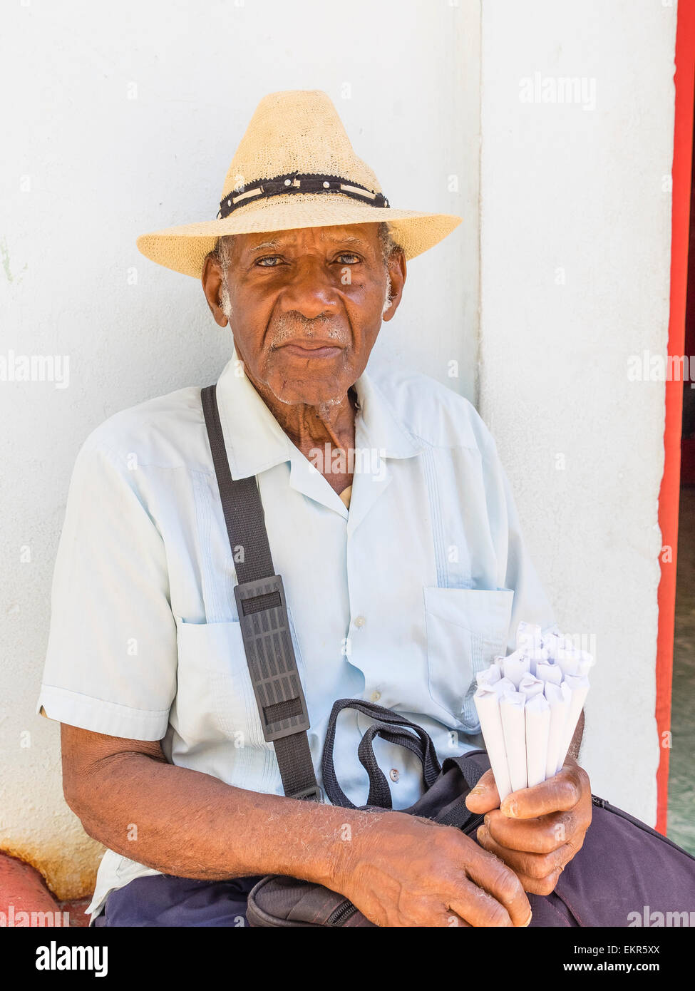 Head and shoulders portrait of a Senior citizen afro-cubaine la vente d'arachides dans les cônes en papier traditionnel chapeau de paille. Banque D'Images
