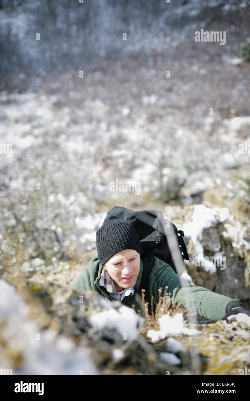 Un homme de la randonnée dans les montagnes de grimper une steep rock face. Banque D'Images