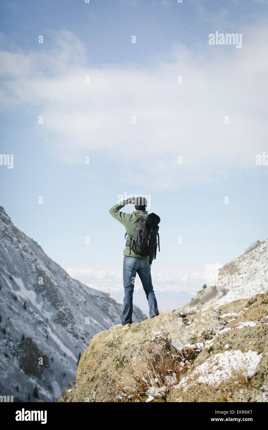 Un homme de la randonnée dans les montagnes debout sur un affleurement à la recherche à la vue. Banque D'Images