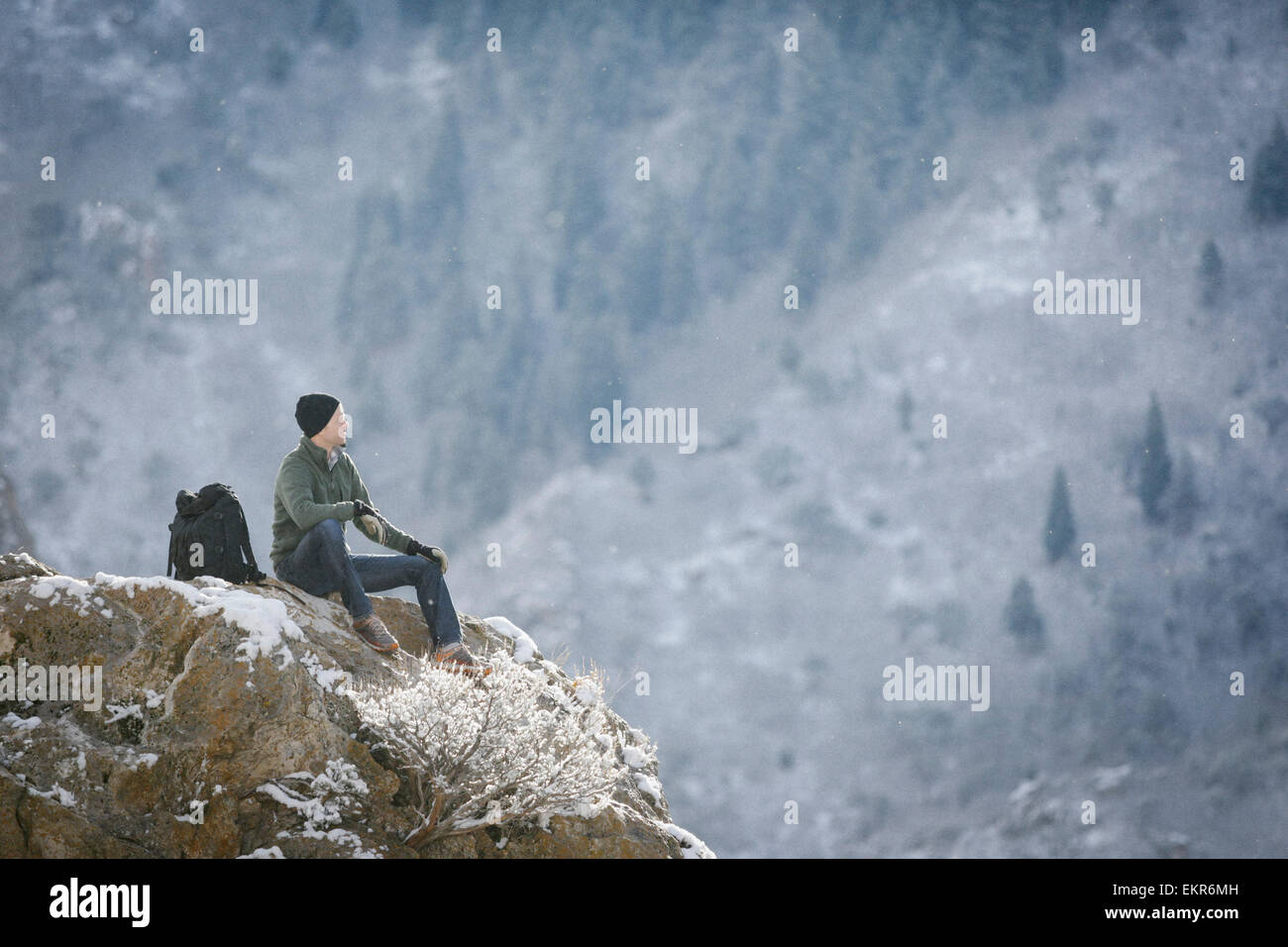 Un homme, un randonneur en montagne, prendre du repos sur un affleurement rocheux au-dessus d'une vallée. Banque D'Images