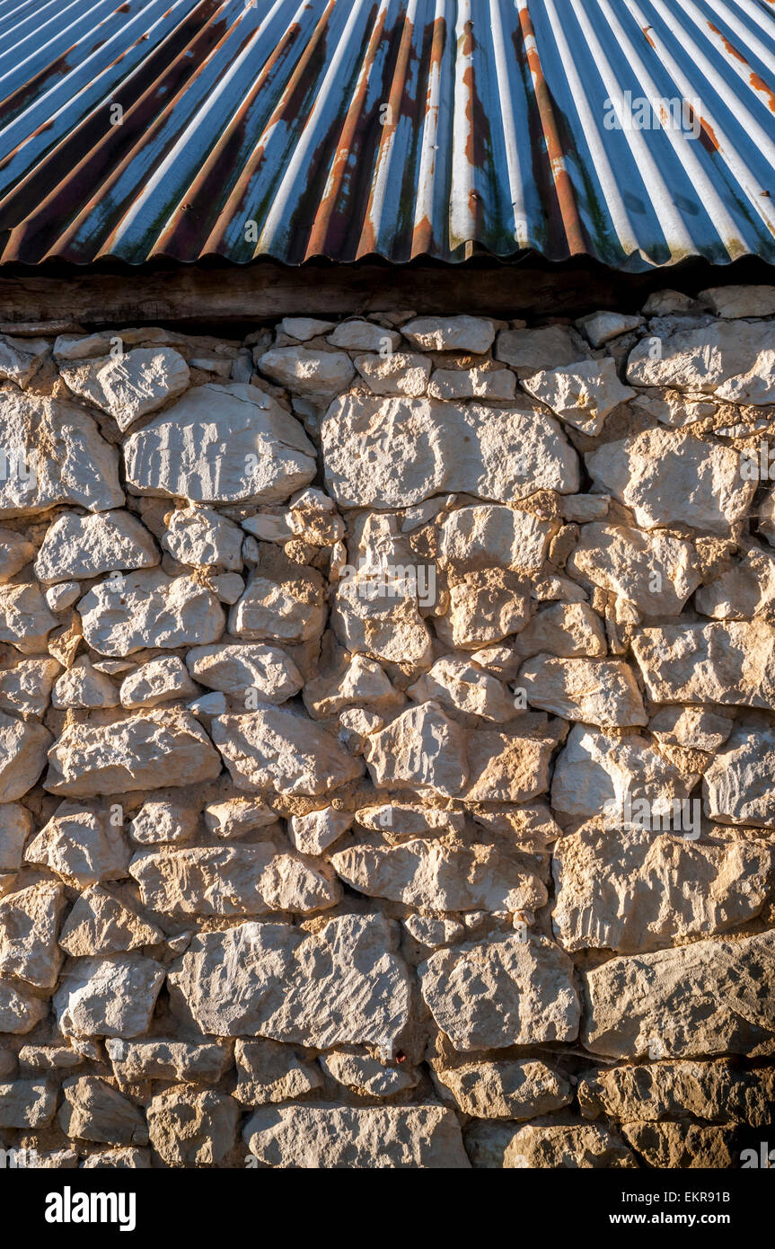 Mur de pierre brute avec toiture en tôle ondulée - France. Banque D'Images
