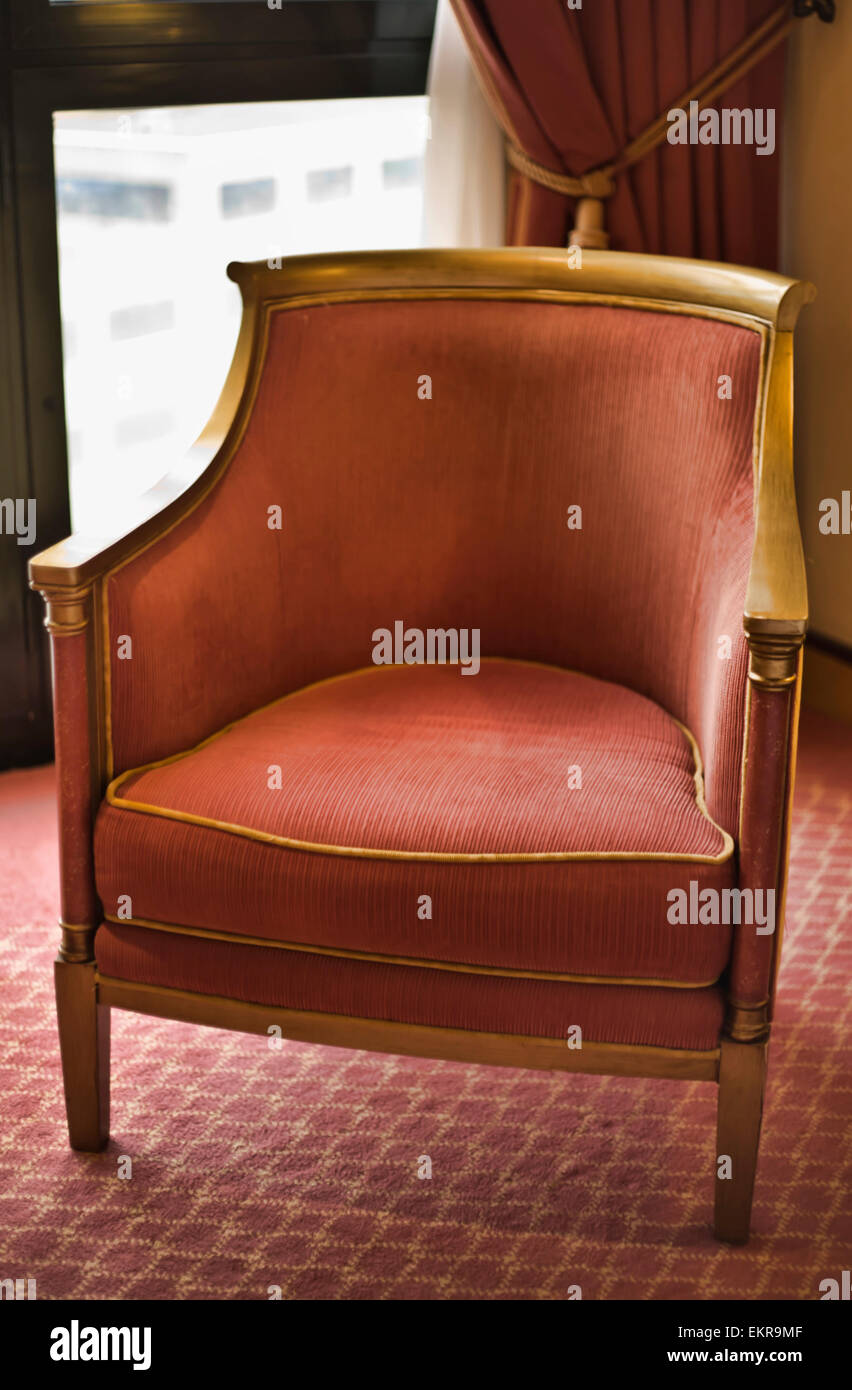 Fauteuil rouge sur un tapis au fond d'une fenêtre Banque D'Images
