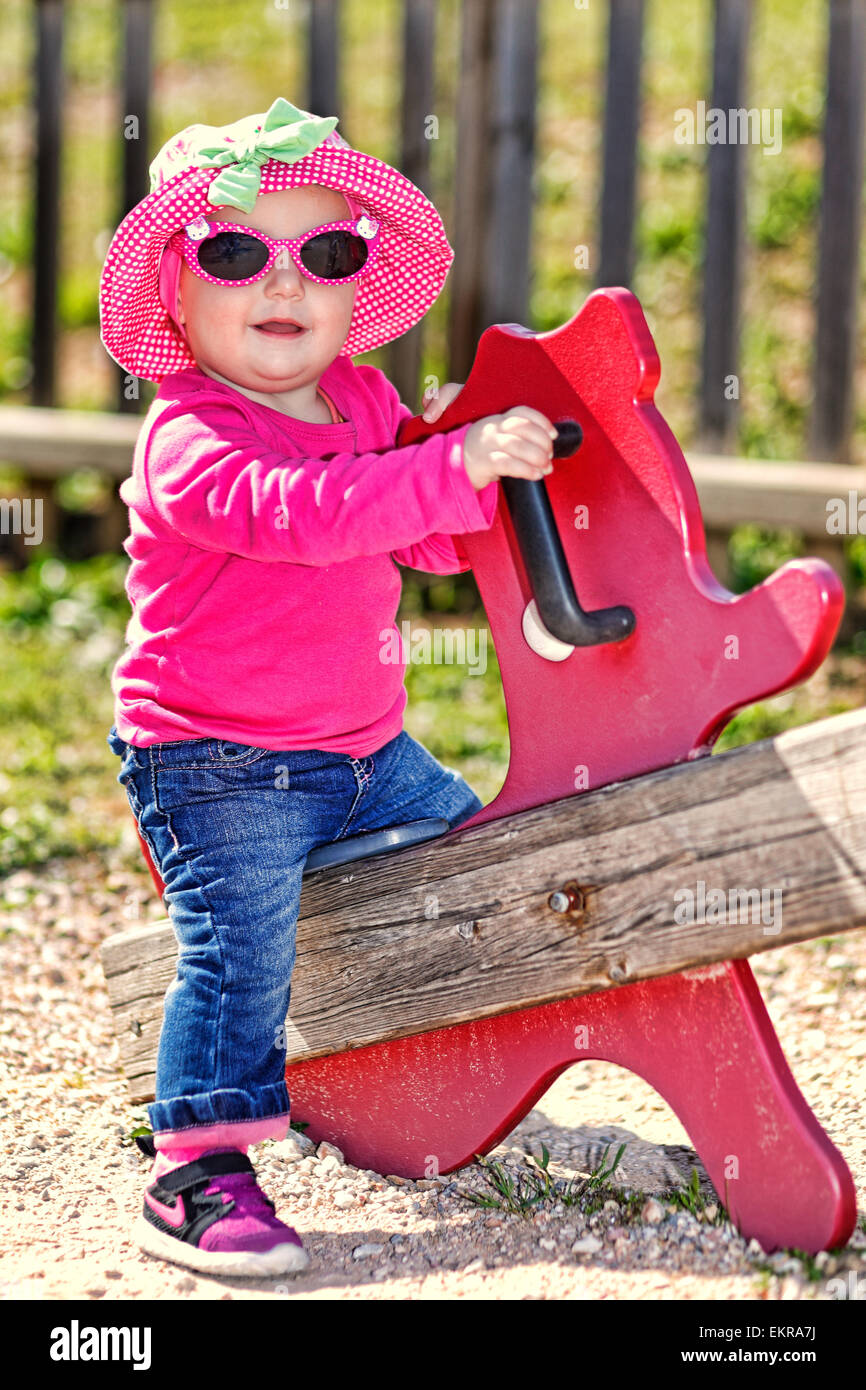 Une jolie petite fille avec des lunettes roses et hat s'amusant Banque D'Images