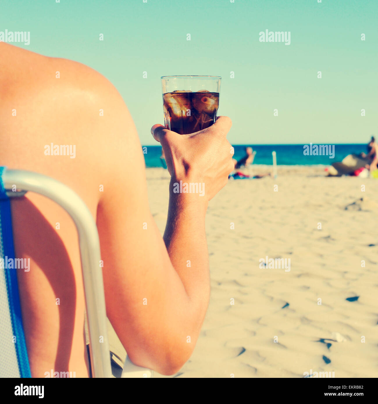 Un jeune homme de race blanche flâner sur la plage avec un verre de boisson coca, avec un effet de filtre Banque D'Images