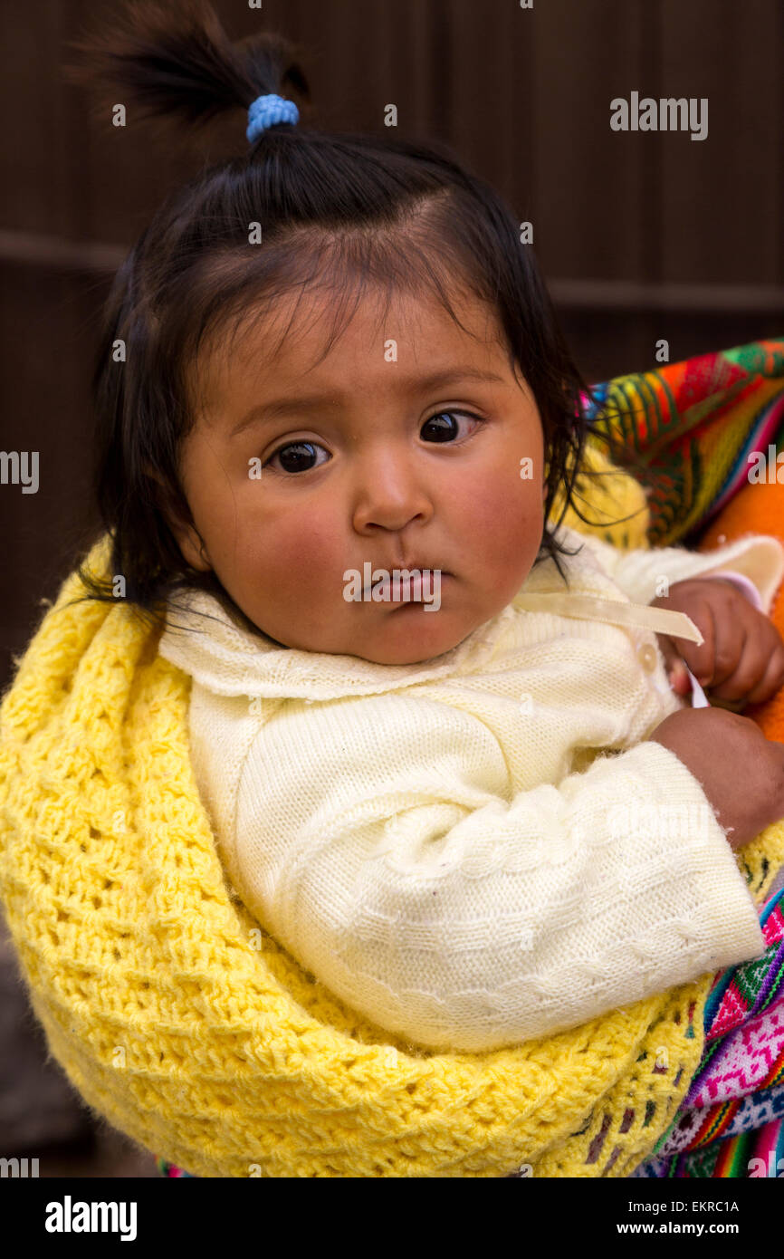 Pérou, Cusco. Jeune fille Quechua en cours sur le dos de sa mère. Banque D'Images