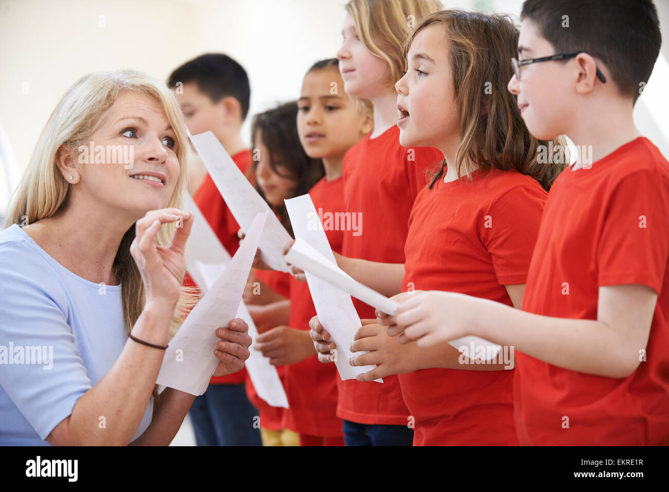 Les enfants en groupe de chant étant encouragé par l'enseignant Banque D'Images Les enfants en groupe de chant étant encouragé par l'enseignant Banque D'Images