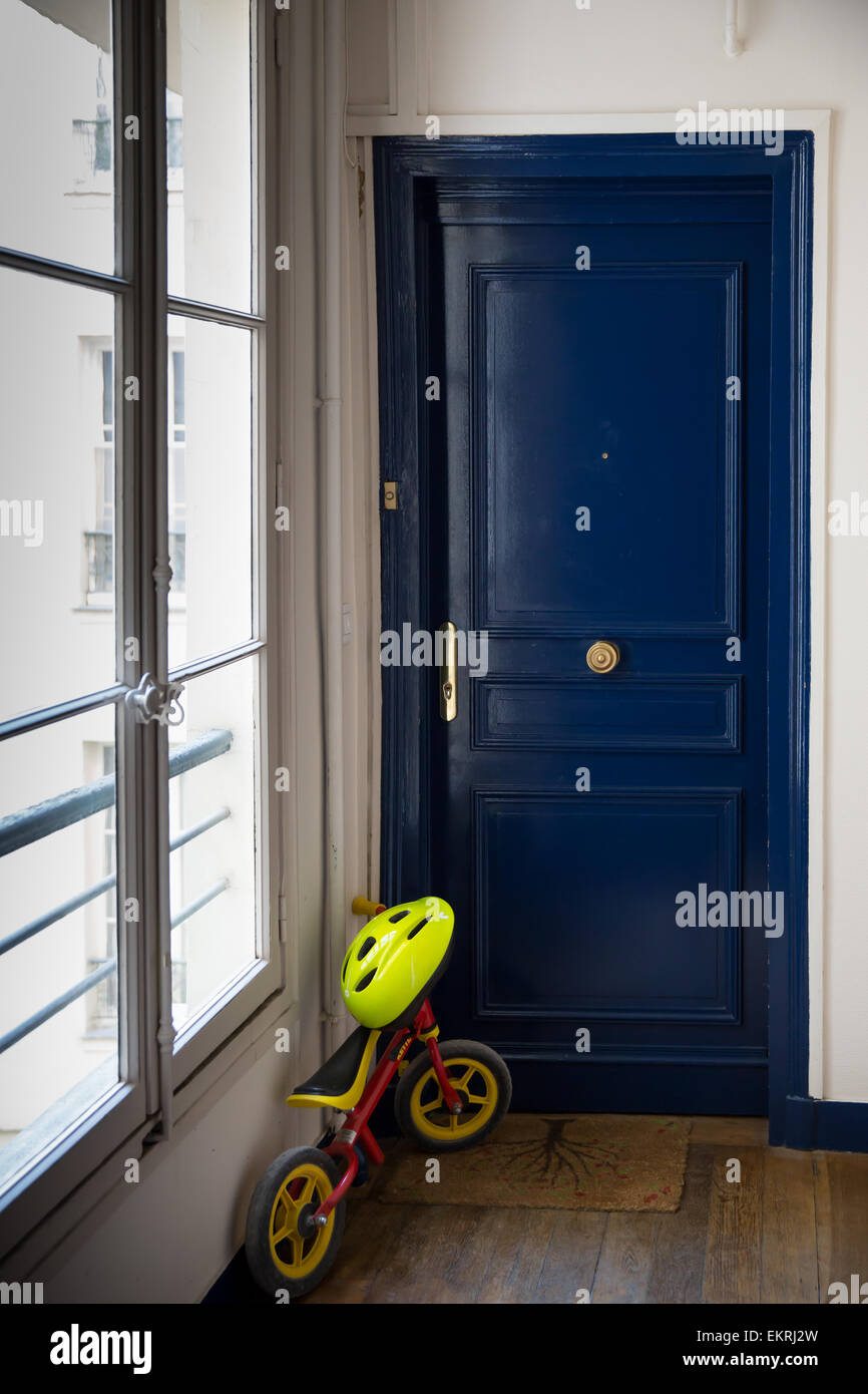 Une porte bleue avec un équilibre de l'enfant location (pas de pédales) et le casque à l'intérieur d'un immeuble d'entrée dans Paris, France Banque D'Images