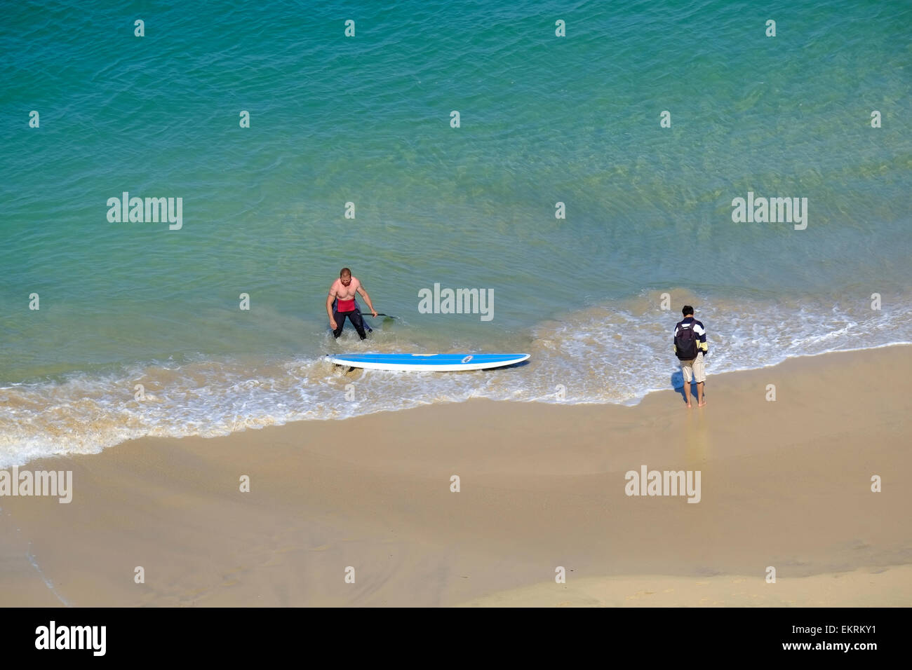 L'homme sur la plage de Porthminster avec planche de surf à St Ives en Cornouailles Banque D'Images