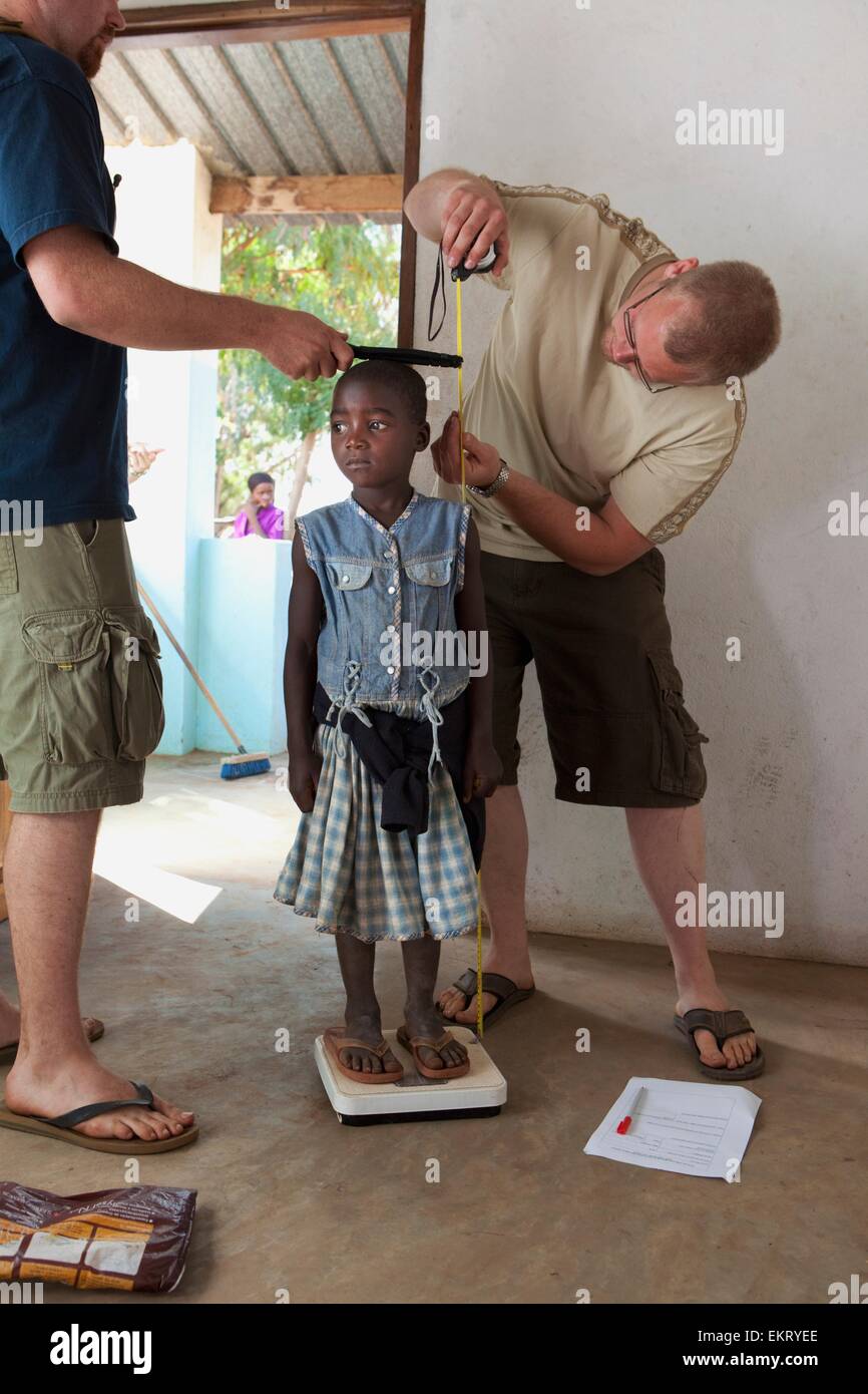 Des travailleurs de la mesure de la taille et le poids d'une jeune fille ; Manica, Mozambique, Africa Banque D'Images