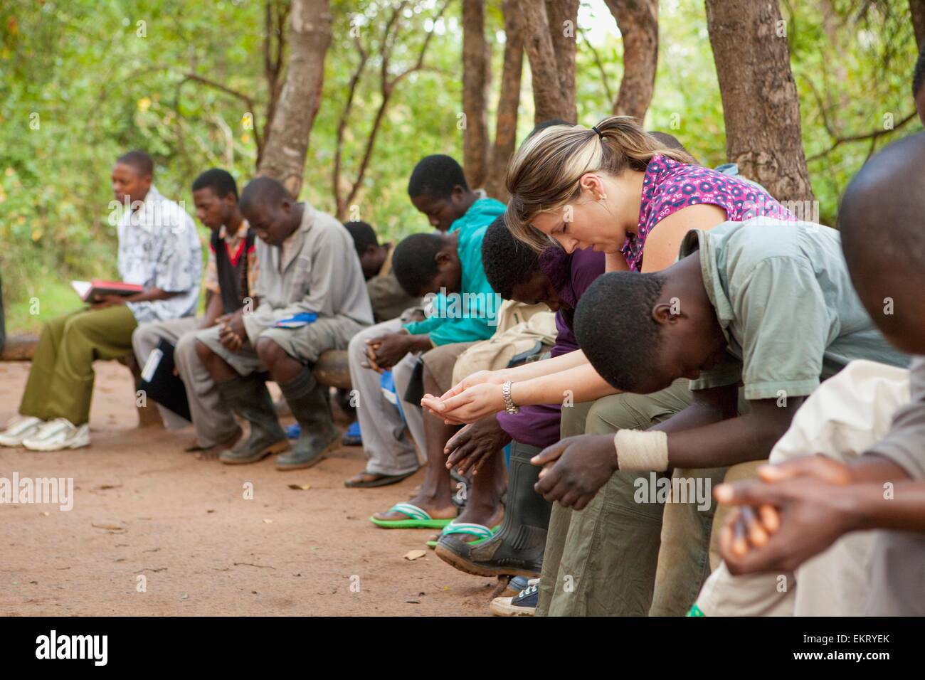 Un groupe de personnes assises à l'extérieur et en priant ensemble ; Manica, Mozambique, Africa Banque D'Images