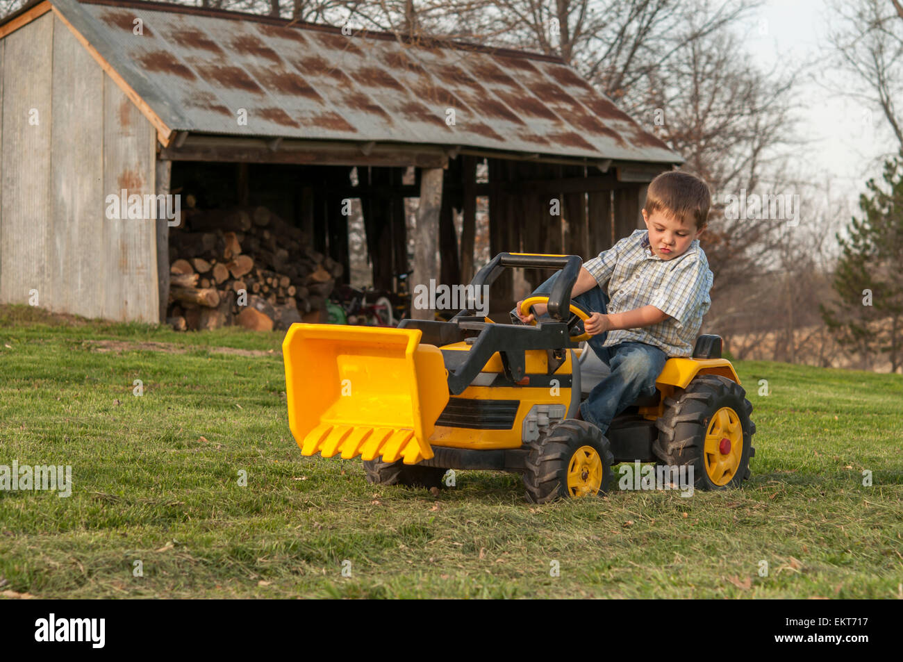 Garçon travaillant par godet de tracteur bûcher dans le pays Banque D'Images