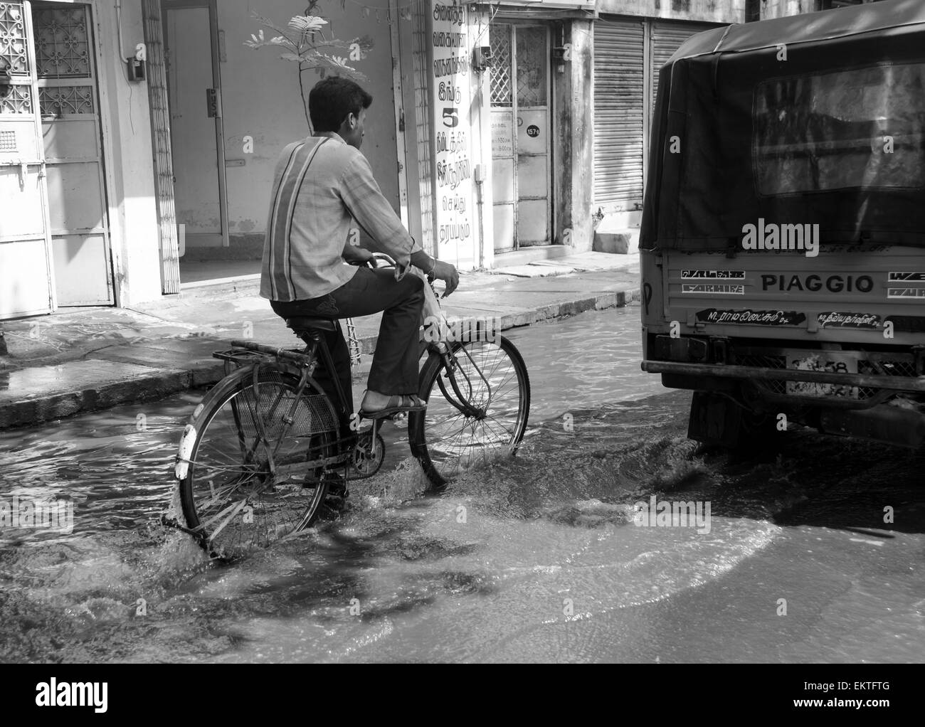 L'Inde, le Tamil Nadu, Madurai cyclistes promenades dans une flaque d'eau dans la route Banque D'Images