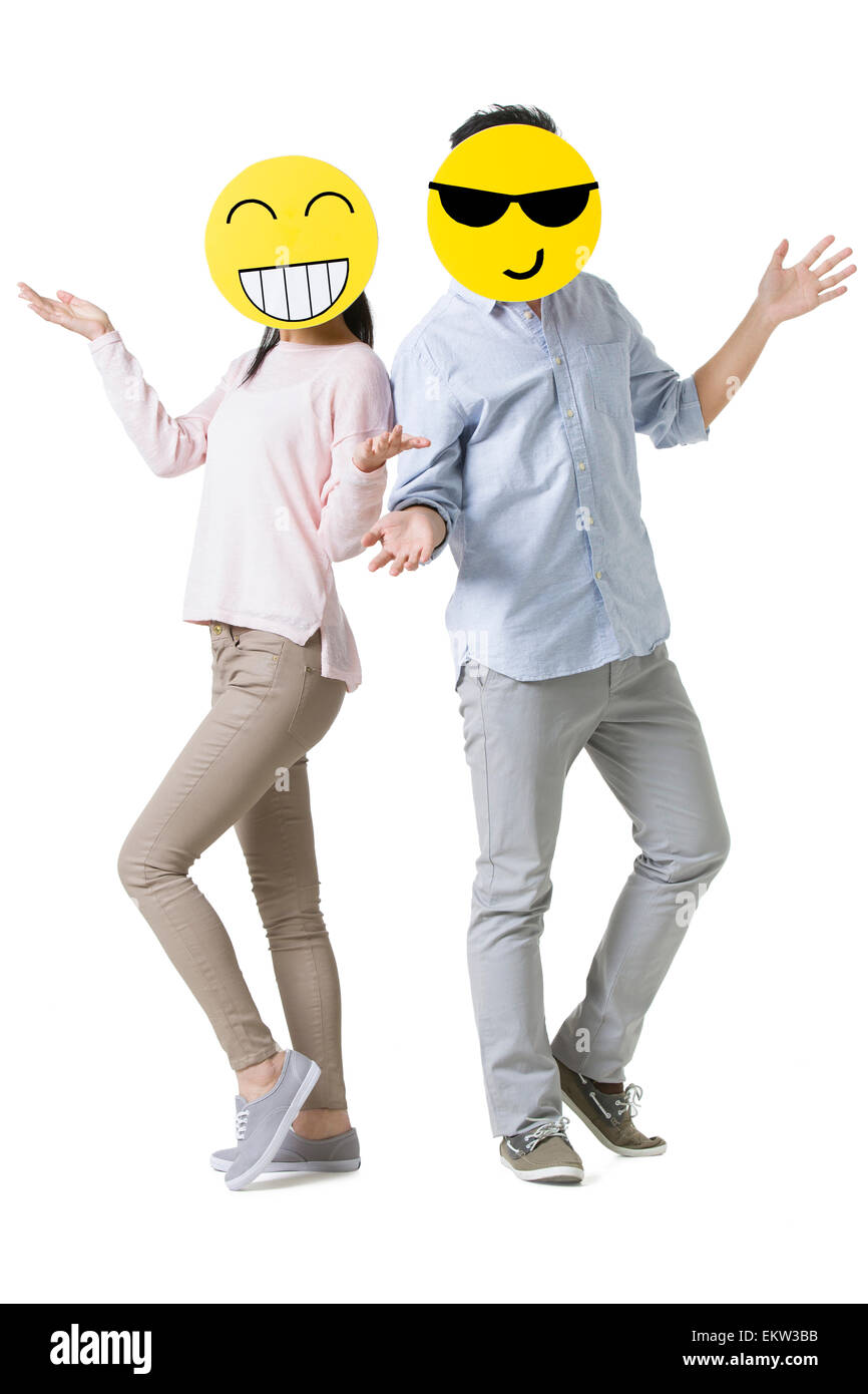Jeune couple avec cartoon émoticône fait face en face de leurs visages Banque D'Images