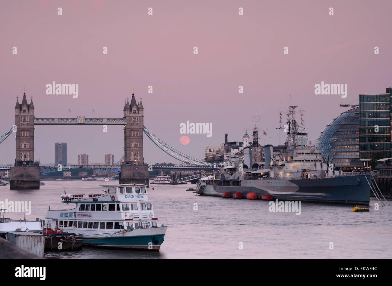 Le ciel devient plus mauve du London Tower Bridge et les bateaux sur la Tamise à mesure que la lune se lève. Banque D'Images
