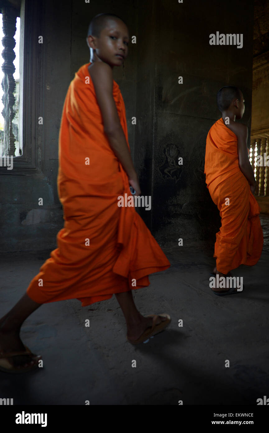 SIEM REAP, Cambodge - 30 octobre 2014 : Novice moines bouddhistes en robe orange marcher pieds nus dans les couloirs sombres à Angkor Wat. Banque D'Images