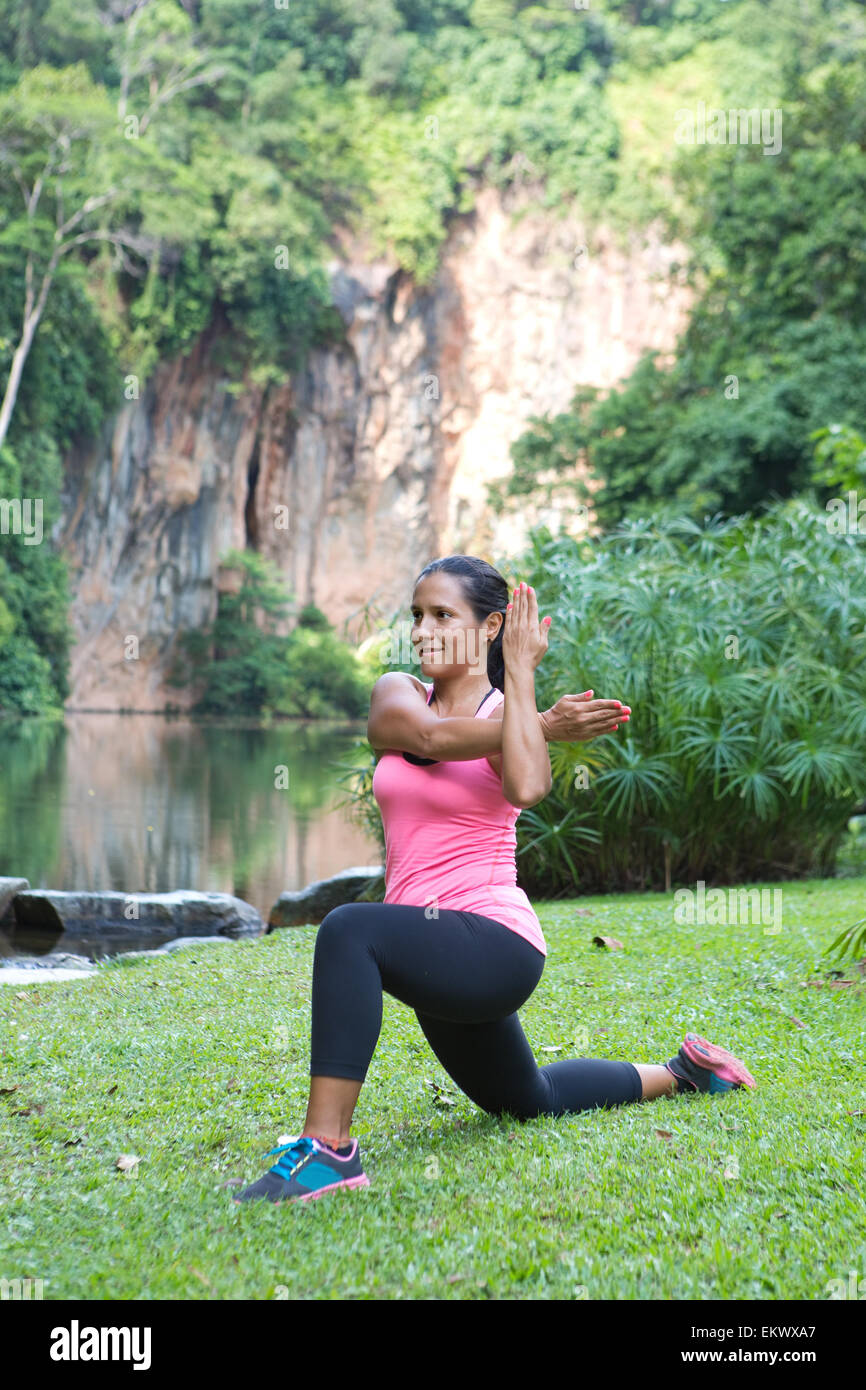 Sporty woman stretching dos triceps du bras tout en faisant une fente dans un parc extérieur. Banque D'Images