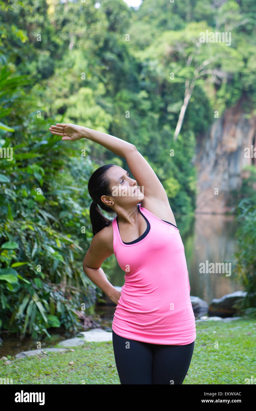 Femme sportive s'étend du côté gauche du corps après l'exercice en extérieur parc Banque D'Images