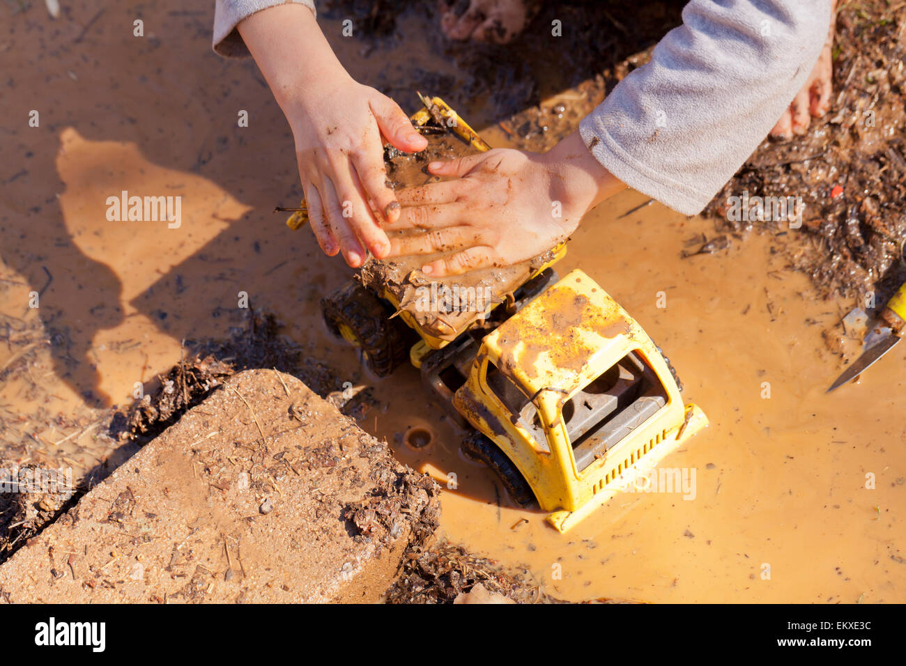 Enfant jouant avec camion jouet dans la boue - USA Banque D'Images