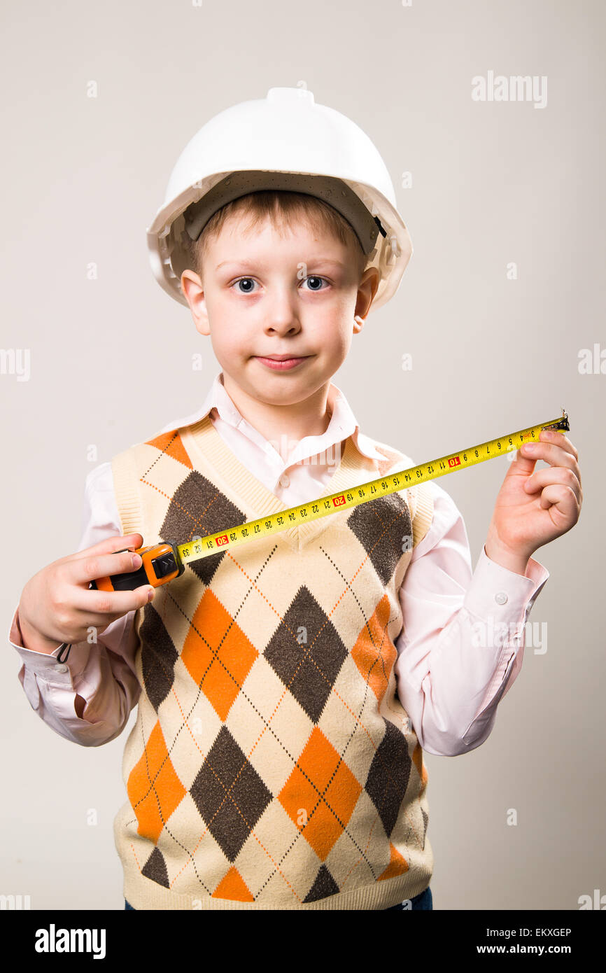 Garçon dans un casque de construction blanc et un ruban à mesurer à la main Banque D'Images