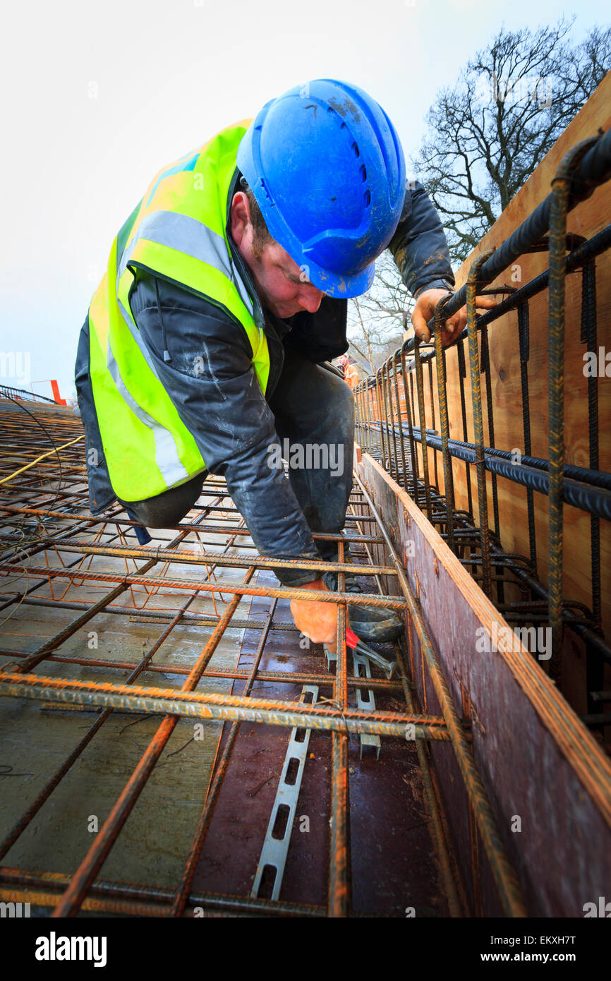 Travailleur de la construction d'attacher les barres d'armature avant de couler du béton sur le toit d'un édifice commercial. Banque D'Images