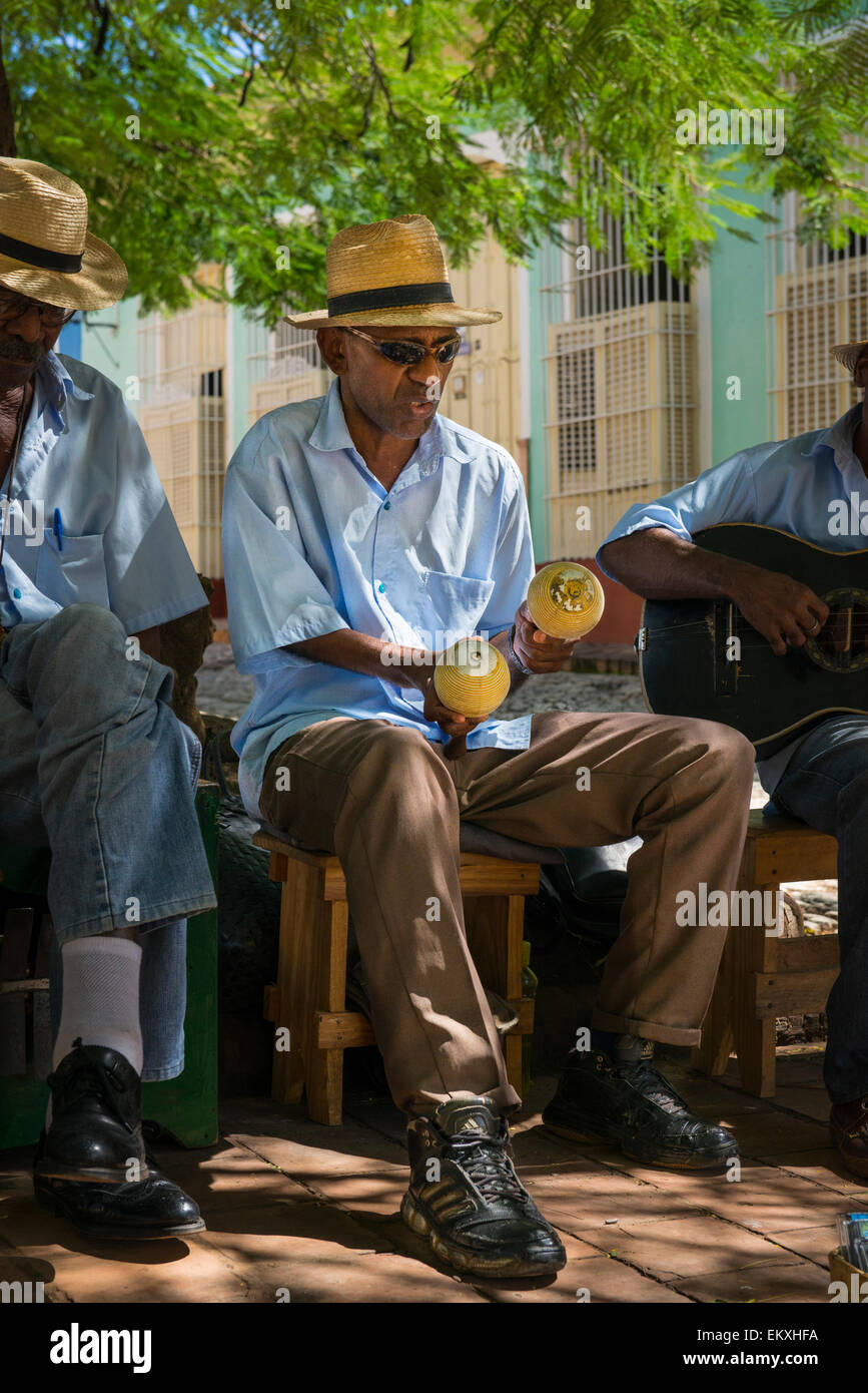 Cuba Trinidad Plaza Mayor, bande de groupe de musique buskers busk musiciens jouent des maracas à l'ombre des arbres par l église de San Francisco Banque D'Images