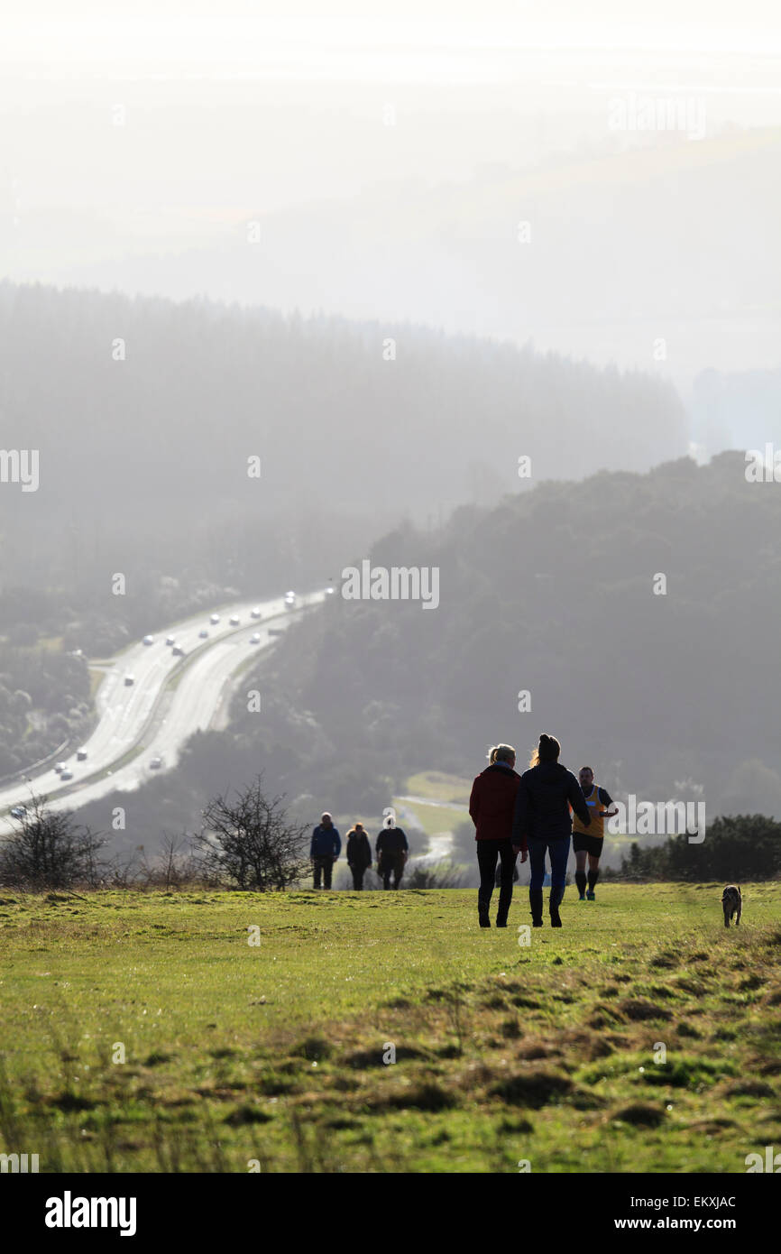 Les gens qui marchent sur le Sud à Butser hill en silhouette avec A3 Trunk road Banque D'Images