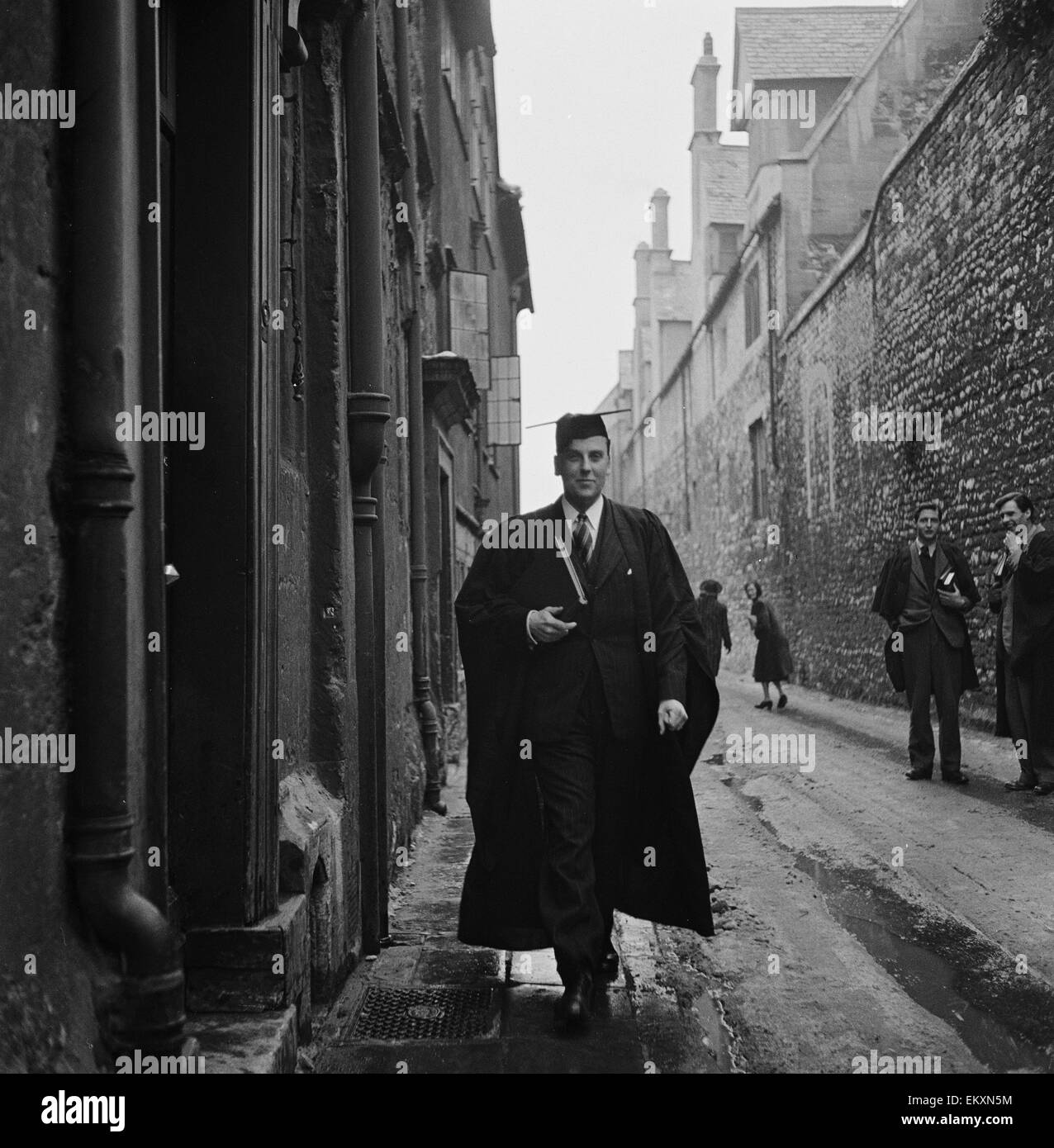 Un étudiant de l'Université d'Oxford, promenades à travers l'une des étroites ruelles de la ville portant des robes de l'université. Vers 1950. Banque D'Images