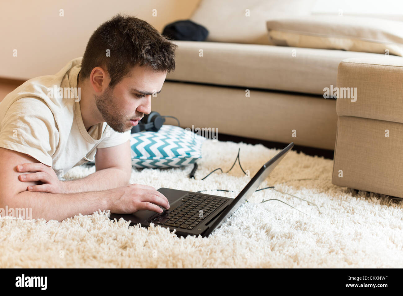 L'homme gisant sur le sol typing on laptop Banque D'Images